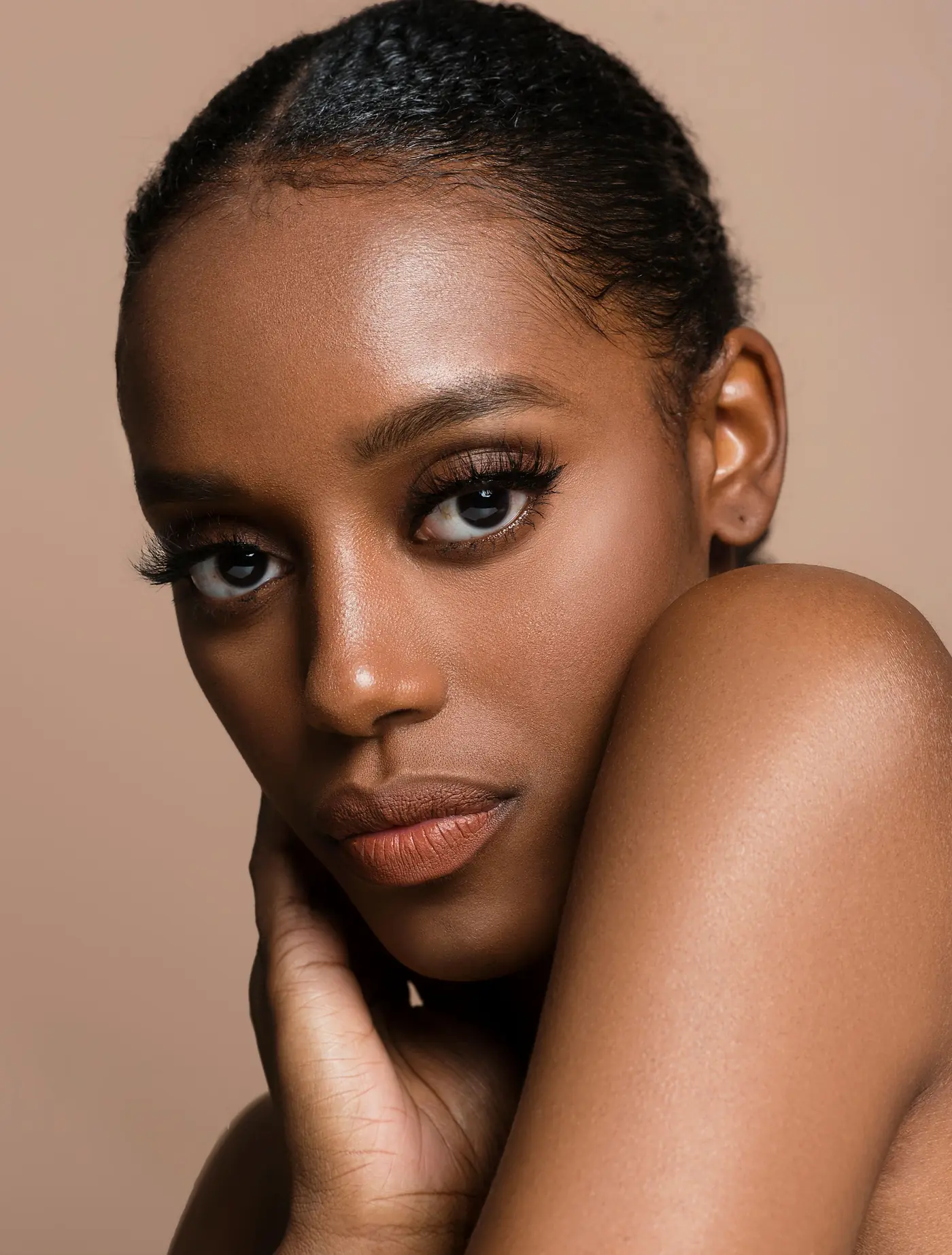 Portrait of a woman with a sleek bun against a warm backdrop