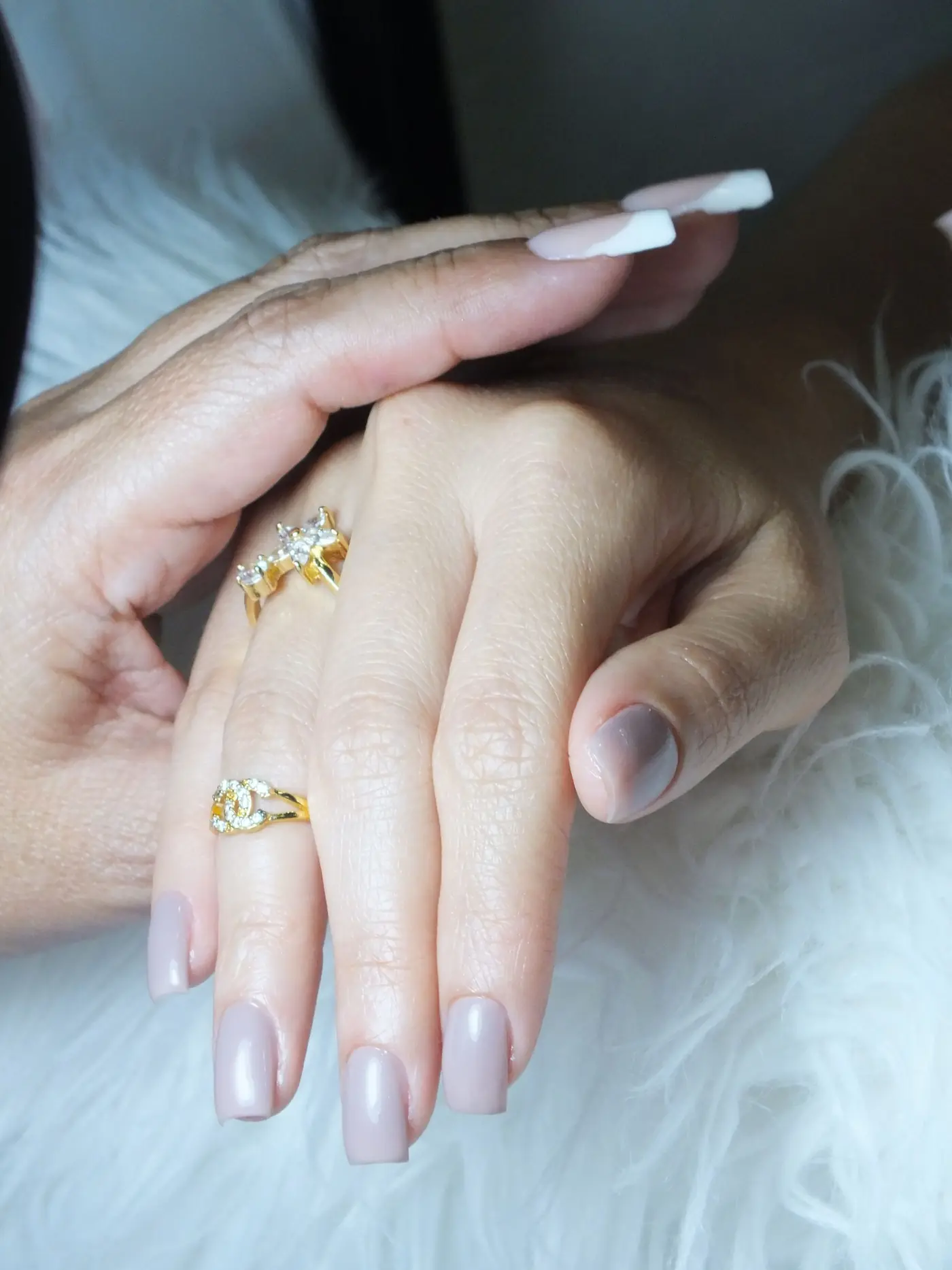 Manicured hands with soft nude nails and gold rings
