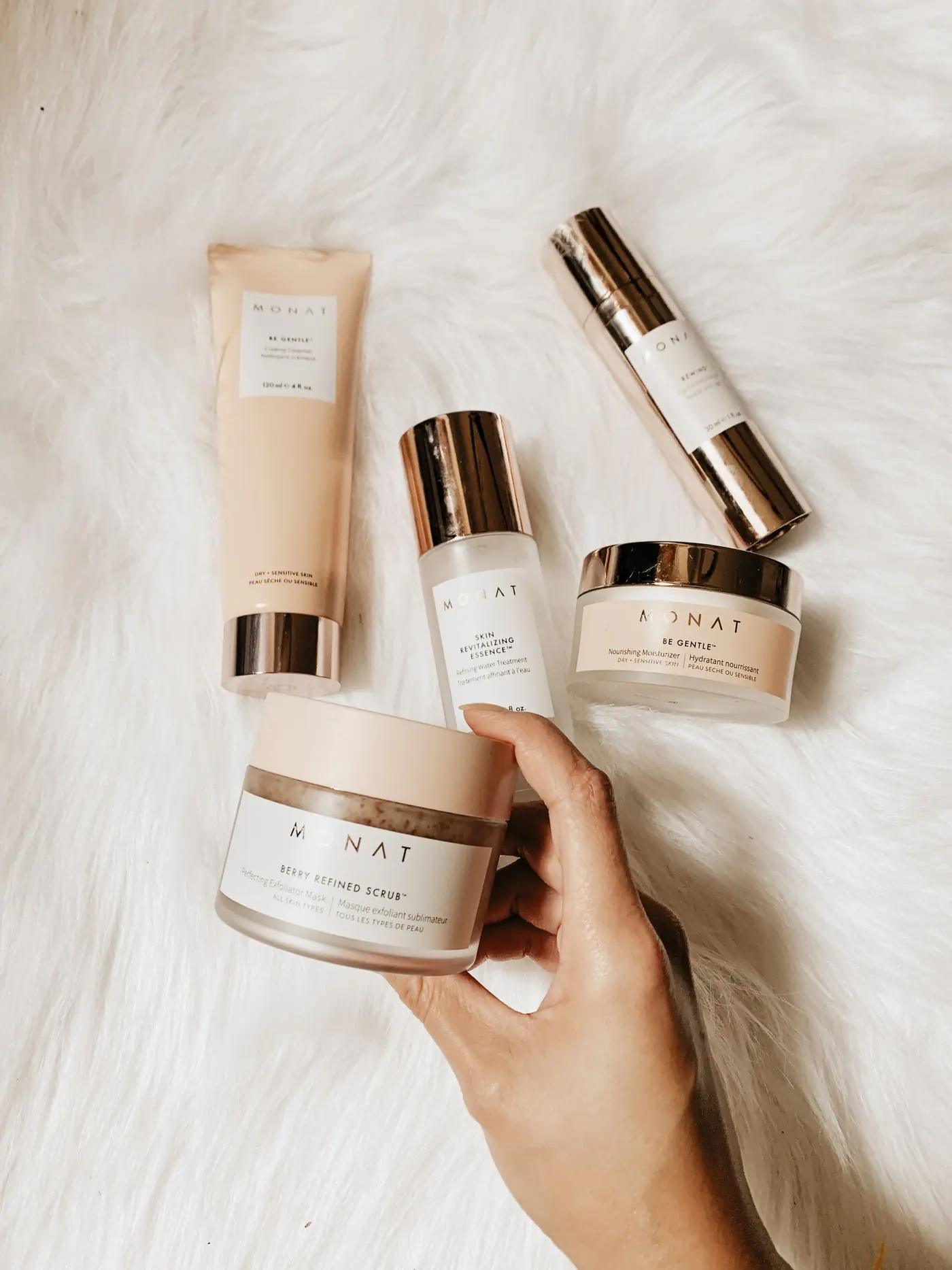Skincare products held over a soft white throw