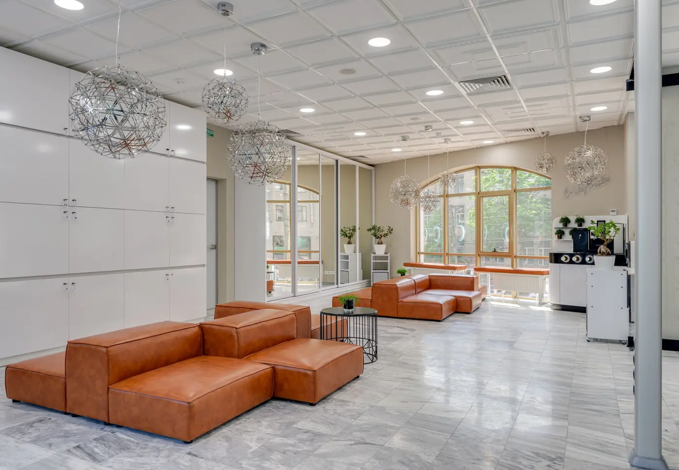 Bright salon lounge with marble floors and soft cognac leather seating