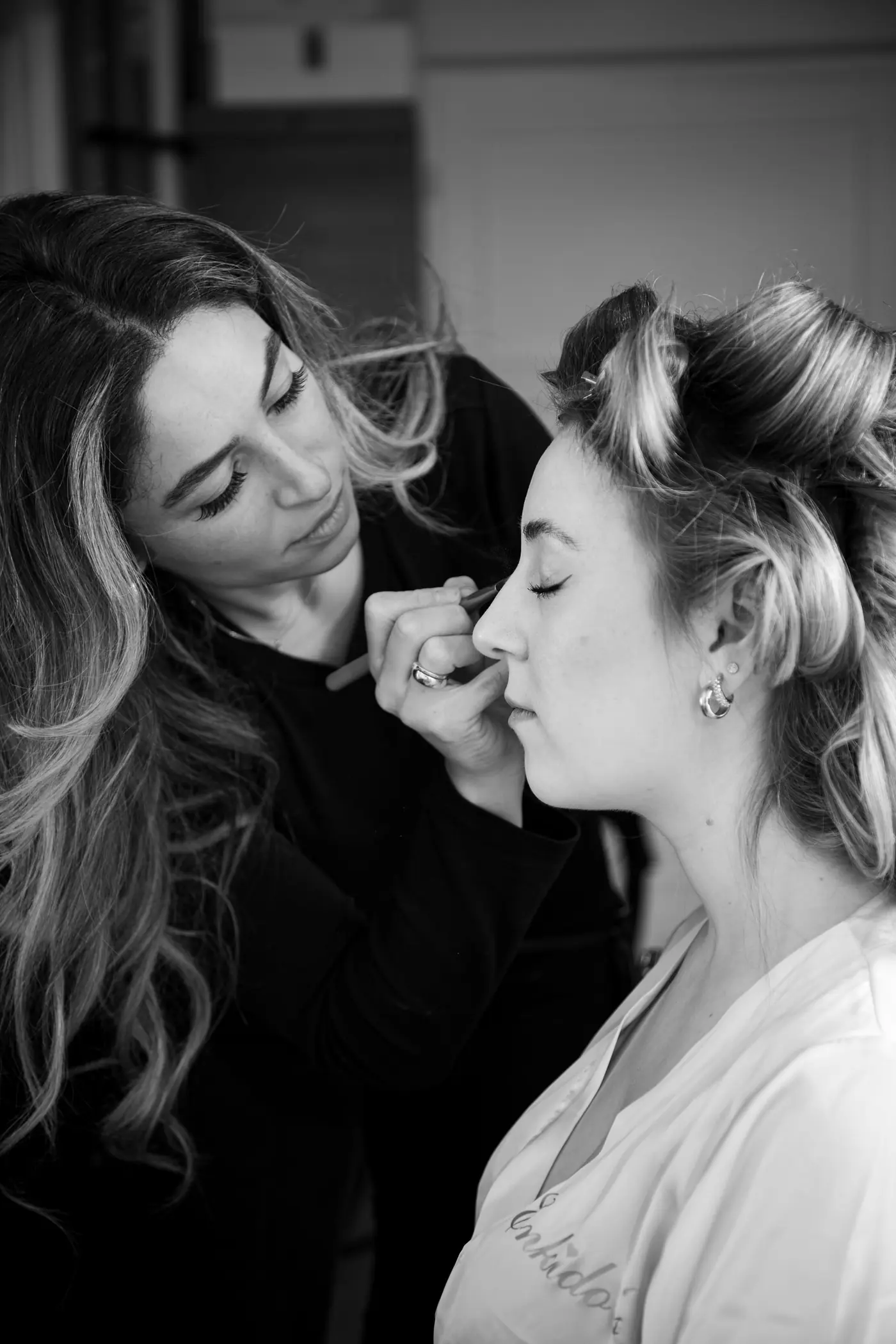 Makeup artist finishing a client’s look, in black and white